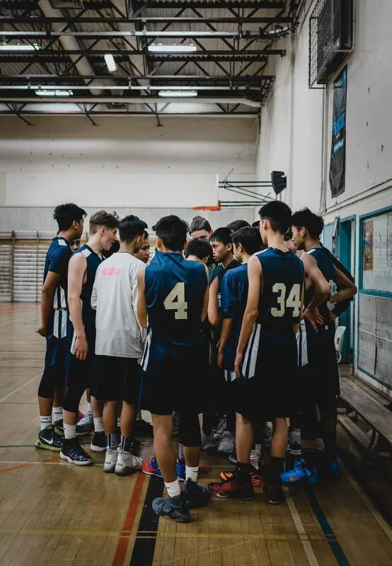 12 year old boys basketball players gathered around their coach in a huddle