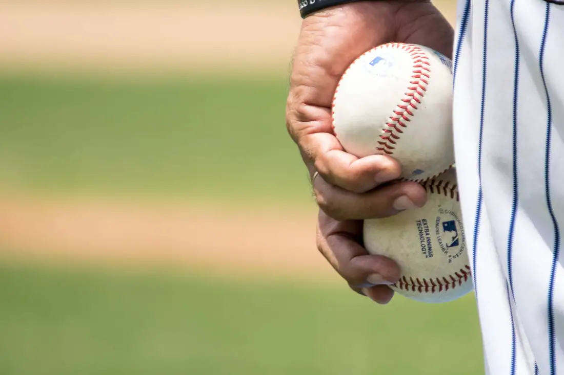 A baseball pitcher holding two baseballs